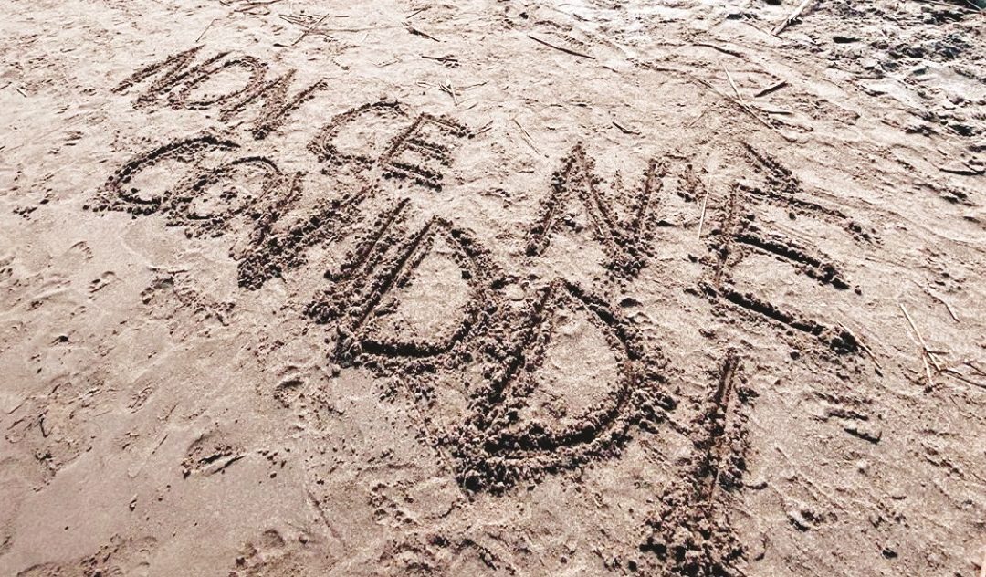 Un’utente di Twitter posta la foto della frase tormentone di Angela Chianello “Non ce n’è Coviddi”, scritta sulla sabbia