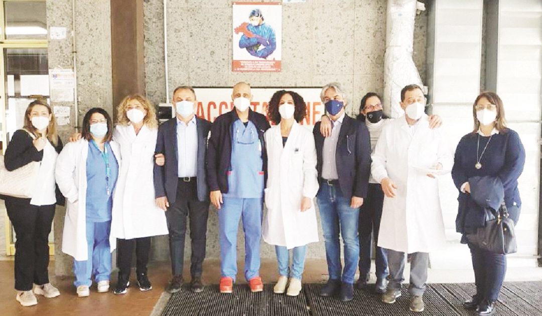 Foto di gruppo di sanitari sotto la targa che testimonia la battaglia contro il covid