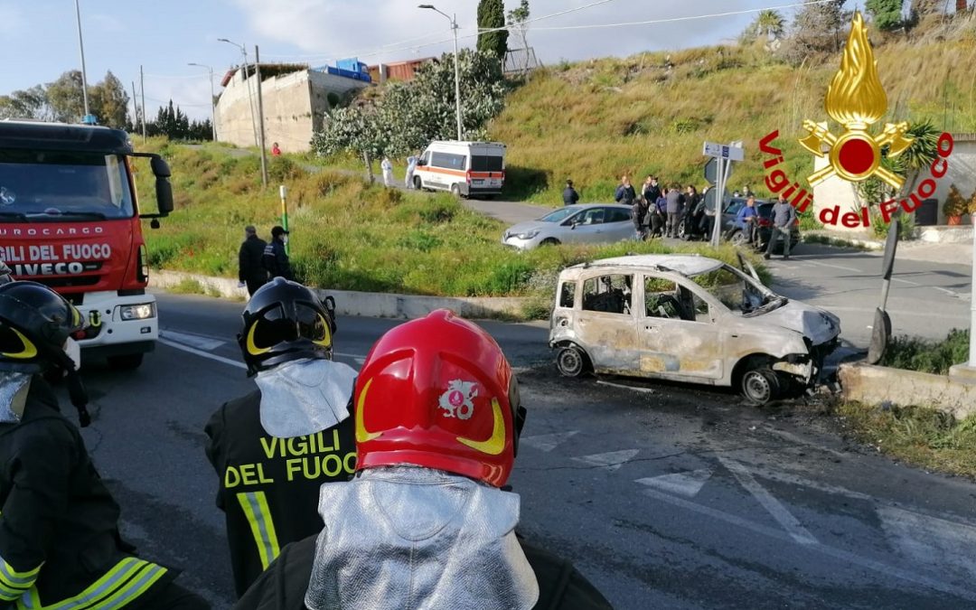 L'auto distrutta dalle fiamme dopo l'impatto e i soccorritori sul posto