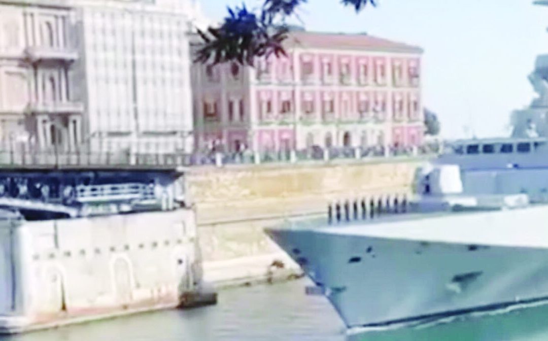 L’ingresso della nave nel porto di Taranto accompagnato dalle proteste di alcune persone sulla banchina